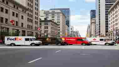 Camions FedEx UPS Purolator et Postes Canada côte à côte dans une rue canadienne